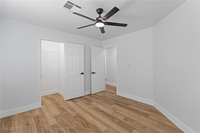 unfurnished bedroom with baseboards, light wood-type flooring, and a spacious closet