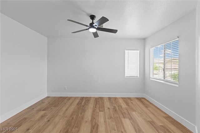 unfurnished room with a ceiling fan, light wood-style flooring, and baseboards