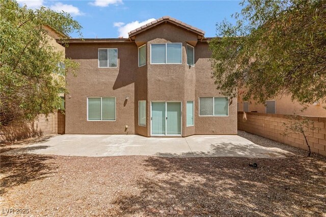 rear view of house with a patio, stucco siding, a fenced backyard, and a tile roof
