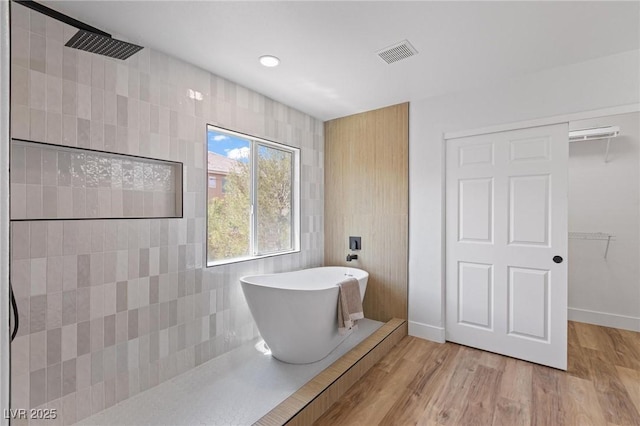 full bath with tiled shower, a freestanding tub, wood finished floors, recessed lighting, and baseboards