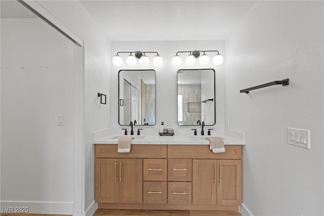 bathroom with baseboards, double vanity, and wood finished floors