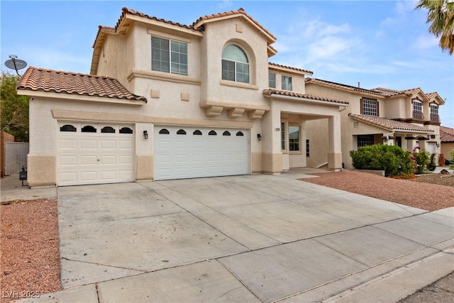 mediterranean / spanish-style home with stucco siding, a tiled roof, driveway, and an attached garage