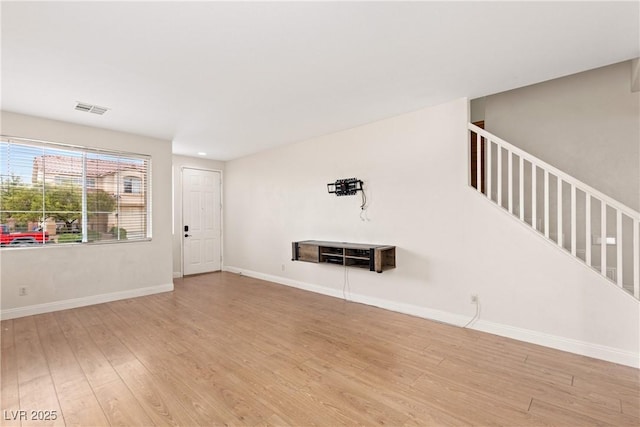 unfurnished living room with wood finished floors, stairs, and baseboards