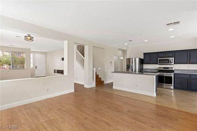 kitchen featuring appliances with stainless steel finishes, open floor plan, recessed lighting, light wood-style flooring, and a kitchen island