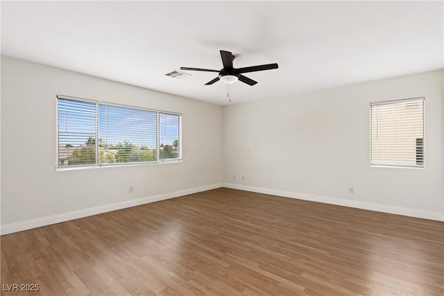 empty room with wood finished floors, a ceiling fan, and baseboards