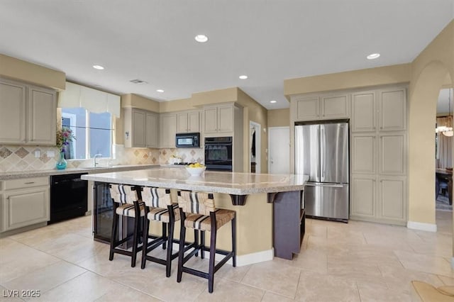 8608 Willow Cabin St, Las Vegas, NV 89131 - kitchen featuring black appliances, a center island, a breakfast bar area, backsplash, and arched walkways