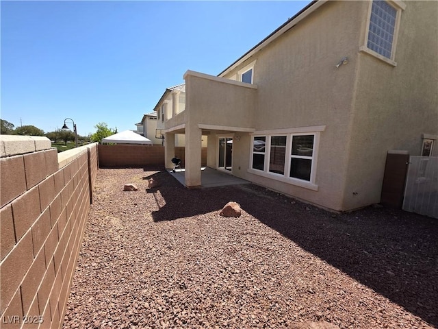 view of property exterior featuring stucco siding, a fenced backyard, and a patio area