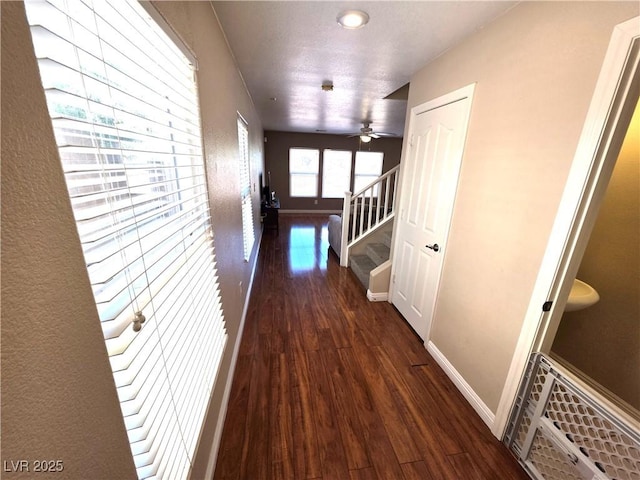 hallway with wood finished floors, baseboards, and stairway