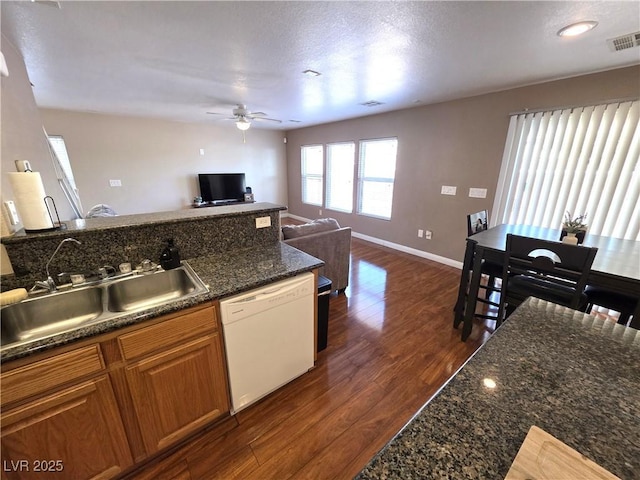 kitchen with dishwasher, a sink, a ceiling fan, brown cabinets, and dark wood-style floors