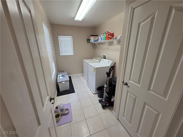 laundry area featuring washing machine and dryer, light tile patterned floors, and baseboards