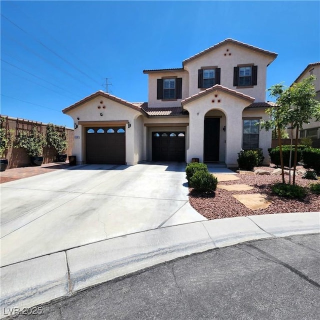 mediterranean / spanish home featuring stucco siding, a tile roof, and driveway