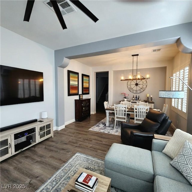 living area featuring a ceiling fan, baseboards, wood finished floors, and a chandelier