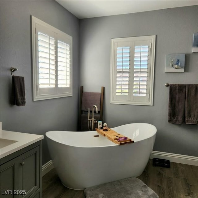 bathroom featuring wood finished floors, baseboards, and a freestanding bath