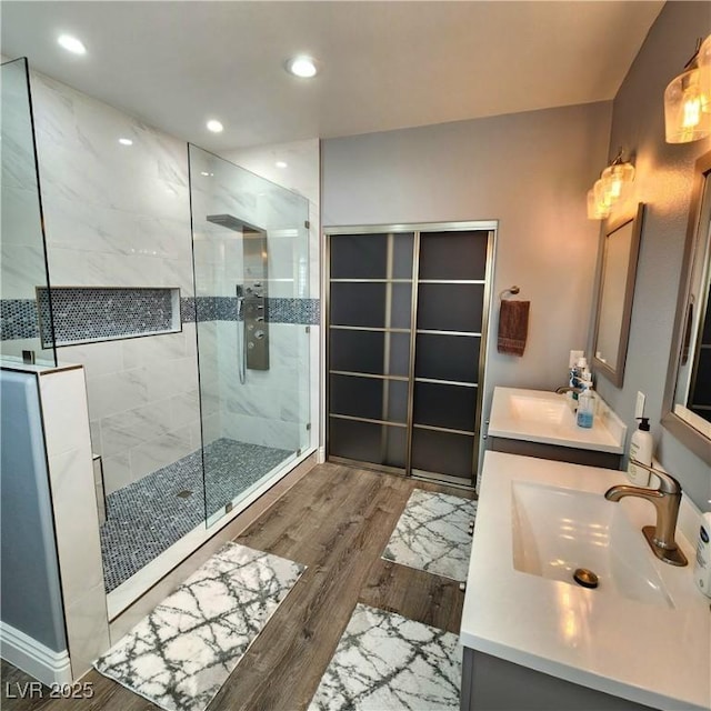 bathroom featuring wood finished floors, a stall shower, recessed lighting, and vanity