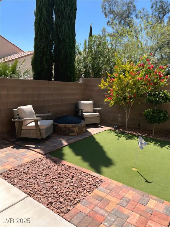 fenced backyard with a putting area and a patio