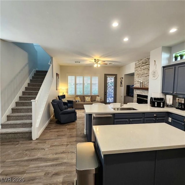 kitchen with a sink, open floor plan, a peninsula, light countertops, and recessed lighting