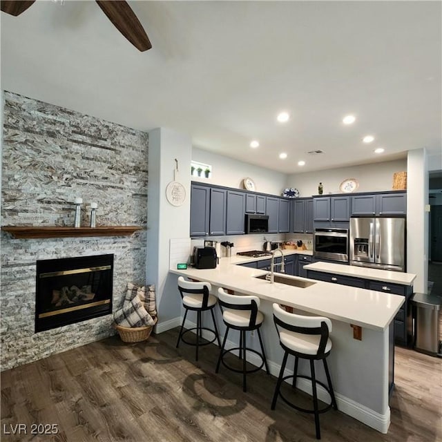 kitchen featuring appliances with stainless steel finishes, a sink, a peninsula, light countertops, and a breakfast bar area