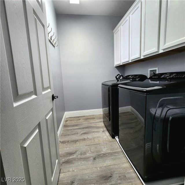 laundry room featuring washer and dryer, cabinet space, wood finished floors, and baseboards