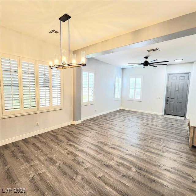 unfurnished dining area featuring a chandelier, wood finished floors, baseboards, and ceiling fan
