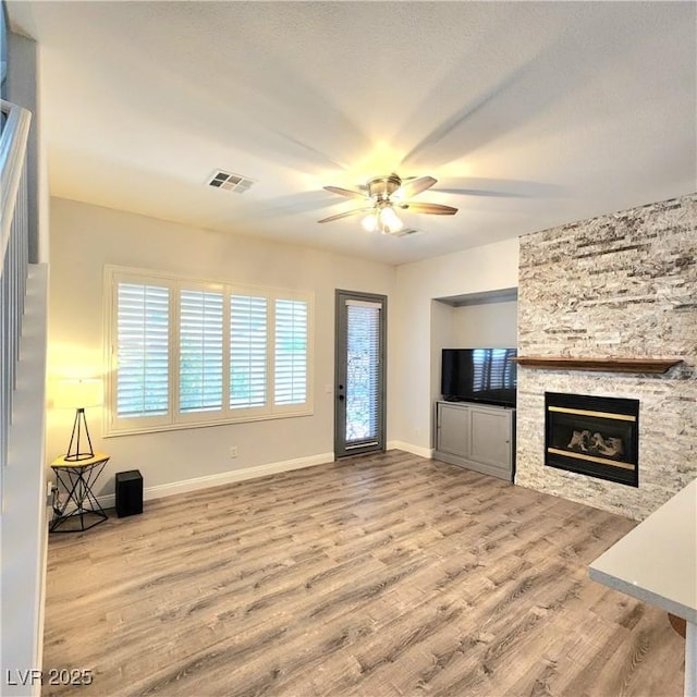 unfurnished living room featuring a ceiling fan, wood finished floors, a fireplace, and baseboards