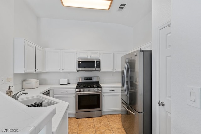688 Castlebridge Ave, Las Vegas, NV 89123 - kitchen with appliances with stainless steel finishes, a sink, white cabinets, tile counters, and high vaulted ceiling