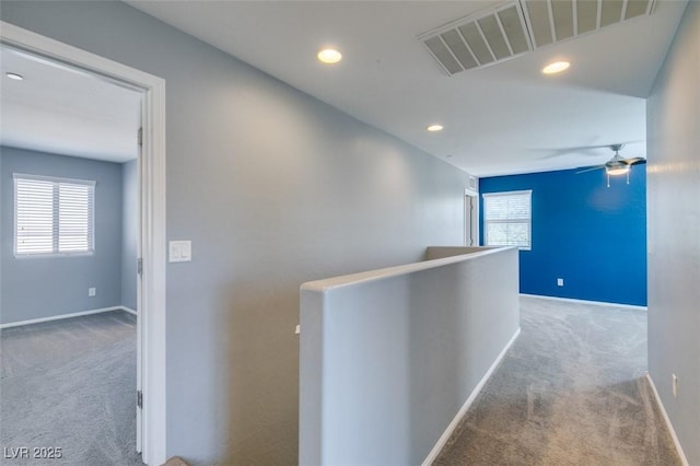 hallway featuring carpet floors, an upstairs landing, baseboards, and recessed lighting