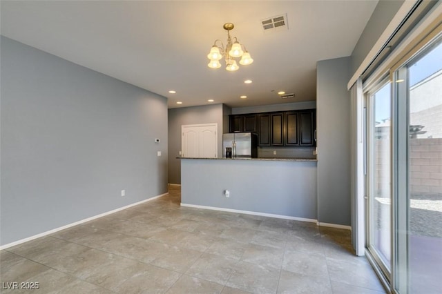 unfurnished living room featuring a chandelier, baseboards, and recessed lighting