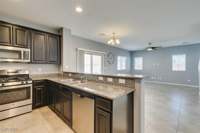 kitchen featuring appliances with stainless steel finishes, a sink, light tile patterned floors, a chandelier, and a peninsula