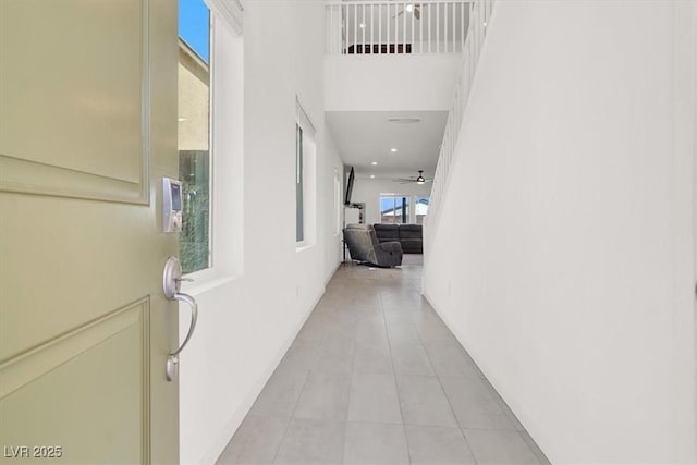 hall with light tile patterned flooring and a towering ceiling