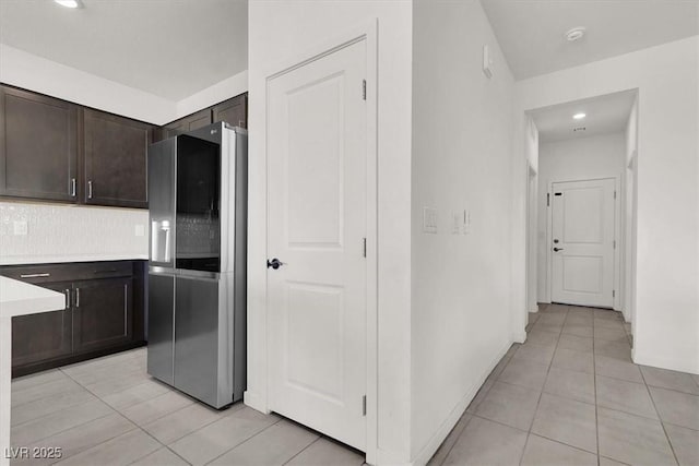 kitchen featuring smart refrigerator, dark brown cabinets, light tile patterned floors, light countertops, and backsplash