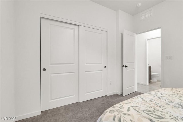 carpeted bedroom featuring a closet and baseboards