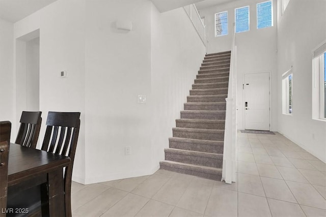stairway with tile patterned flooring and a towering ceiling