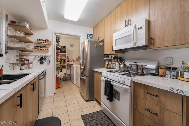7885 W Flamingo Rd Unit 1161, Las Vegas, NV 89147 - kitchen featuring appliances with stainless steel finishes, light tile patterned flooring, open shelves, light stone countertops, and a sink