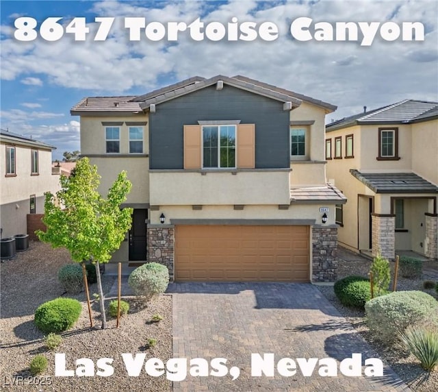 view of front of house featuring stucco siding, stone siding, a garage, and decorative driveway