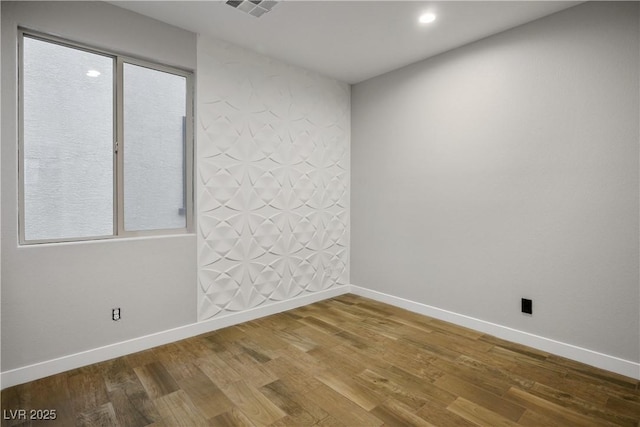 empty room with wood finished floors, baseboards, and recessed lighting