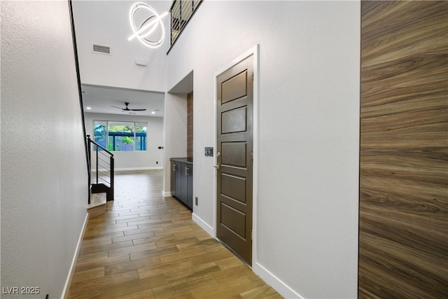 hallway with baseboards, wood finished floors, and stairway