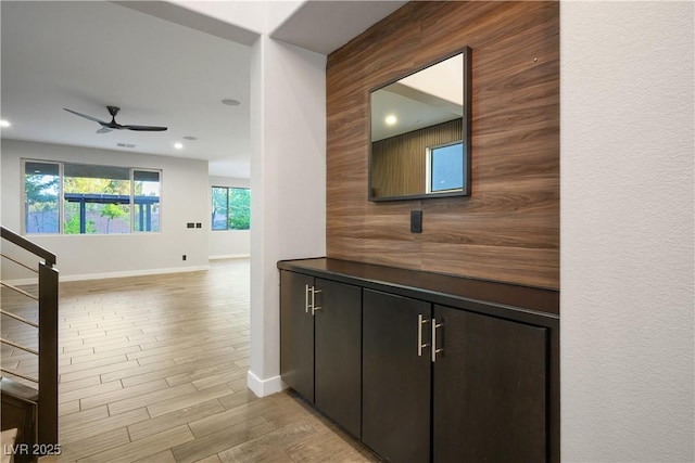hall with baseboards, light wood finished floors, recessed lighting, and stairs
