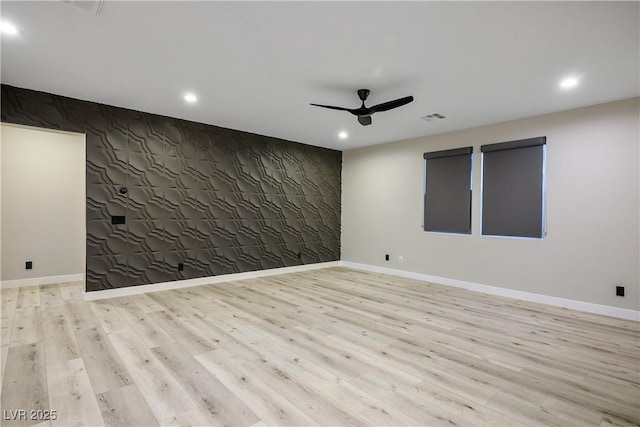 spare room with a ceiling fan, recessed lighting, wood finished floors, baseboards, and an accent wall