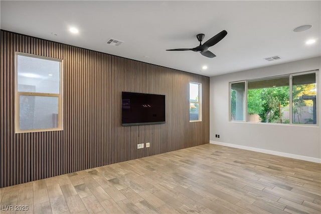 unfurnished living room featuring ceiling fan, wood finished floors, recessed lighting, baseboards, and wood walls