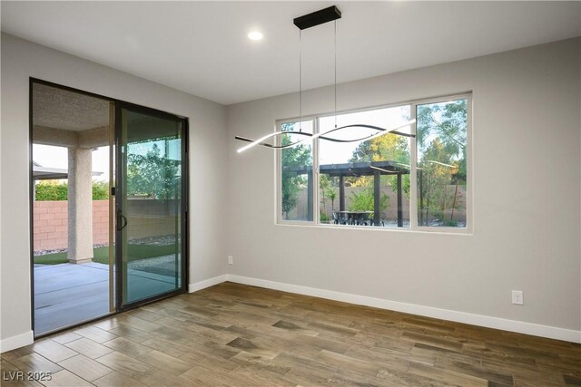 unfurnished dining area with baseboards, wood finished floors, and recessed lighting