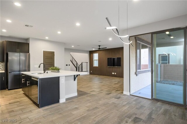 kitchen with freestanding refrigerator, light countertops, dishwasher, recessed lighting, and light wood-style flooring