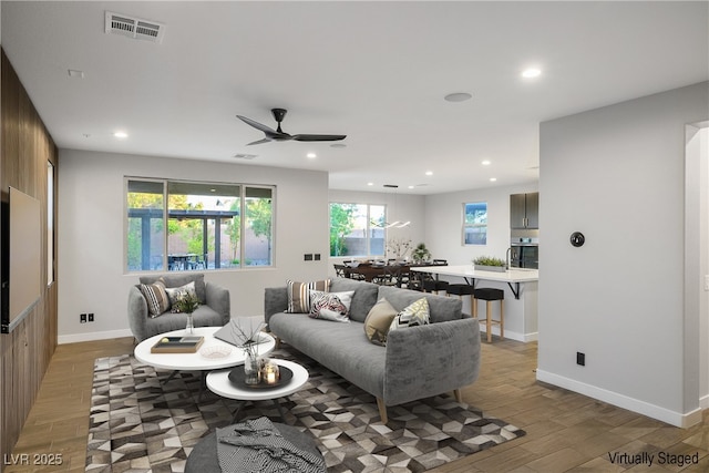 living area featuring light wood-style flooring, recessed lighting, ceiling fan, and baseboards