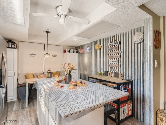 dining space featuring light wood-style floors, a textured ceiling, and a ceiling fan