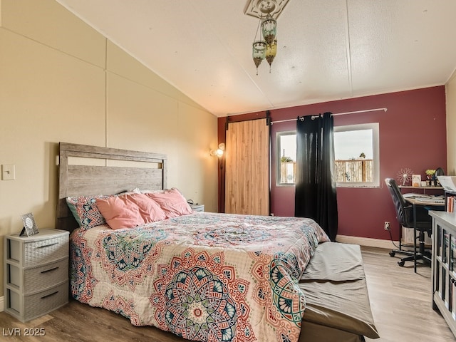 bedroom featuring wood finished floors, lofted ceiling, and baseboards