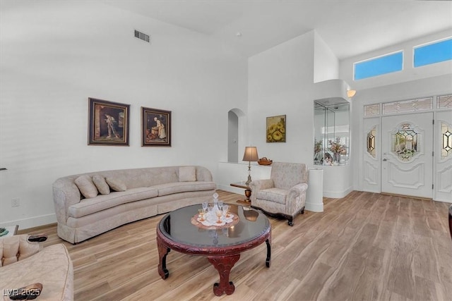9916 Netherton Dr, Las Vegas, NV 89134 - living room featuring arched walkways, a towering ceiling, baseboards, and wood finished floors