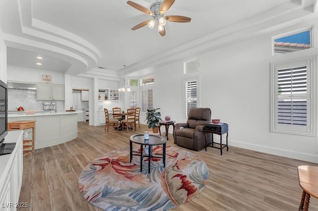 9916 Netherton Dr, Las Vegas, NV 89134 - living area featuring a tray ceiling, ceiling fan, light wood finished floors, and baseboards