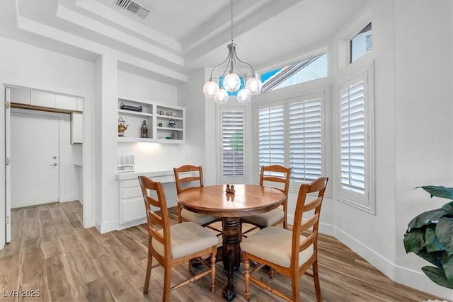 9916 Netherton Dr, Las Vegas, NV 89134 - dining area with a tray ceiling, light wood-style floors, a chandelier, and plenty of natural light