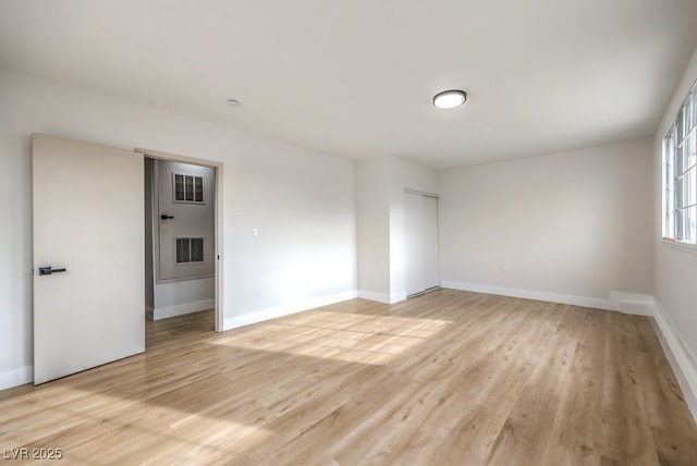 spare room with baseboards and light wood-type flooring