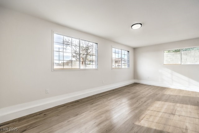 spare room with plenty of natural light, wood finished floors, and baseboards