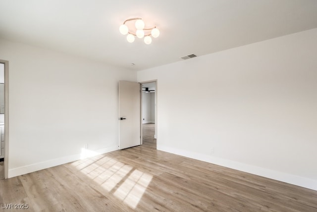 spare room with wood finished floors, baseboards, and a chandelier